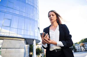 Profissional usando smartphone em frente a edifício corporativo moderno